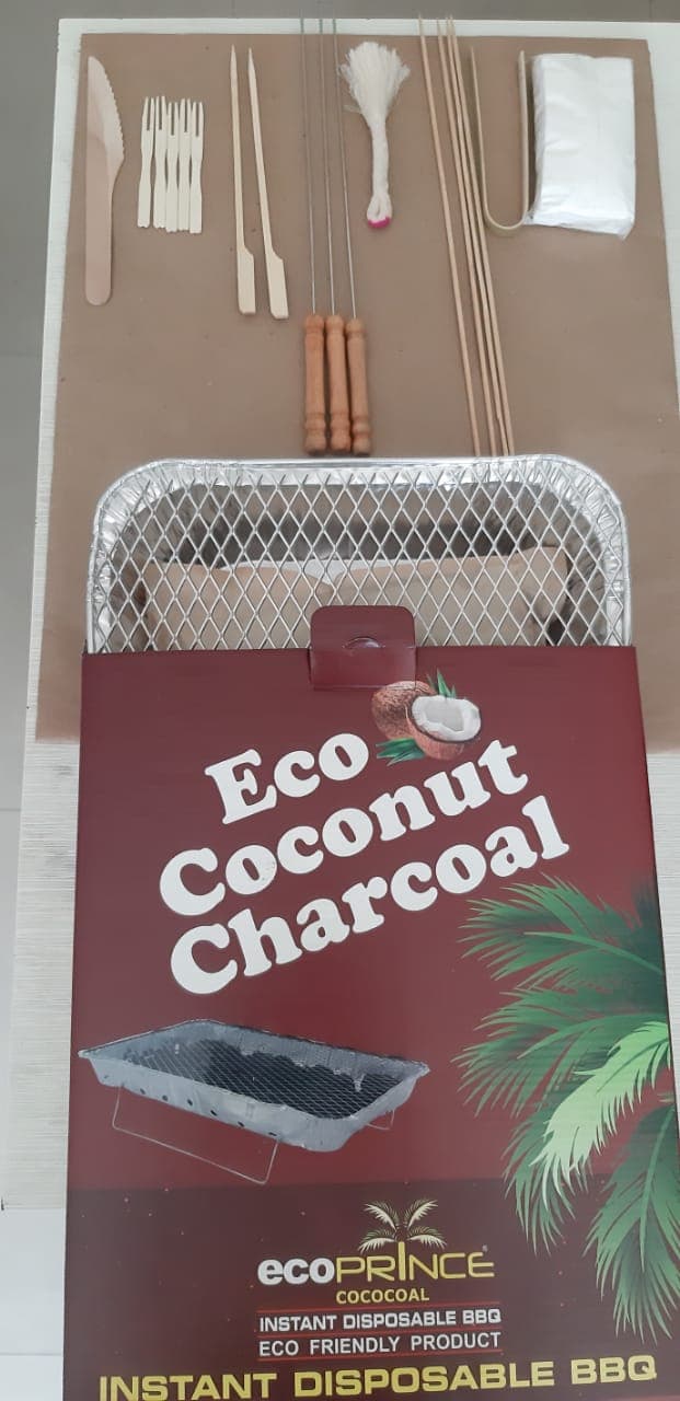Kit laid out: foil tray with grill, wooden cutlery, skewers, tongs, fire starter and Eco Coconut Charcoal pack